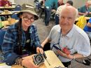 ARRL member Kat Ricker, KF7KAT (left), builds an end-fed half-wave antenna during one of the workshops offered at 2023 SEA-PAC. ARRL Alaska Section Manager David Stevens, KL7EB (right) was among the team of instructors who assisted with the kit building.